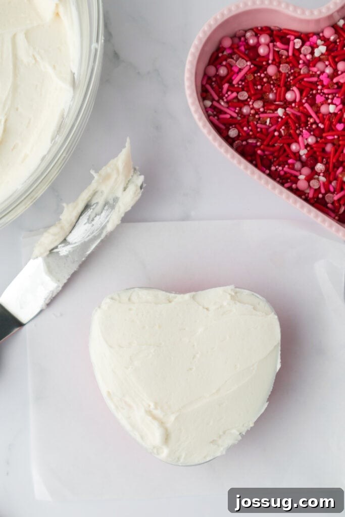Valentine's Day Mini Treat Cake 16 Heart shaped cake fully coated with a smooth layer of white frosting on a cutting board