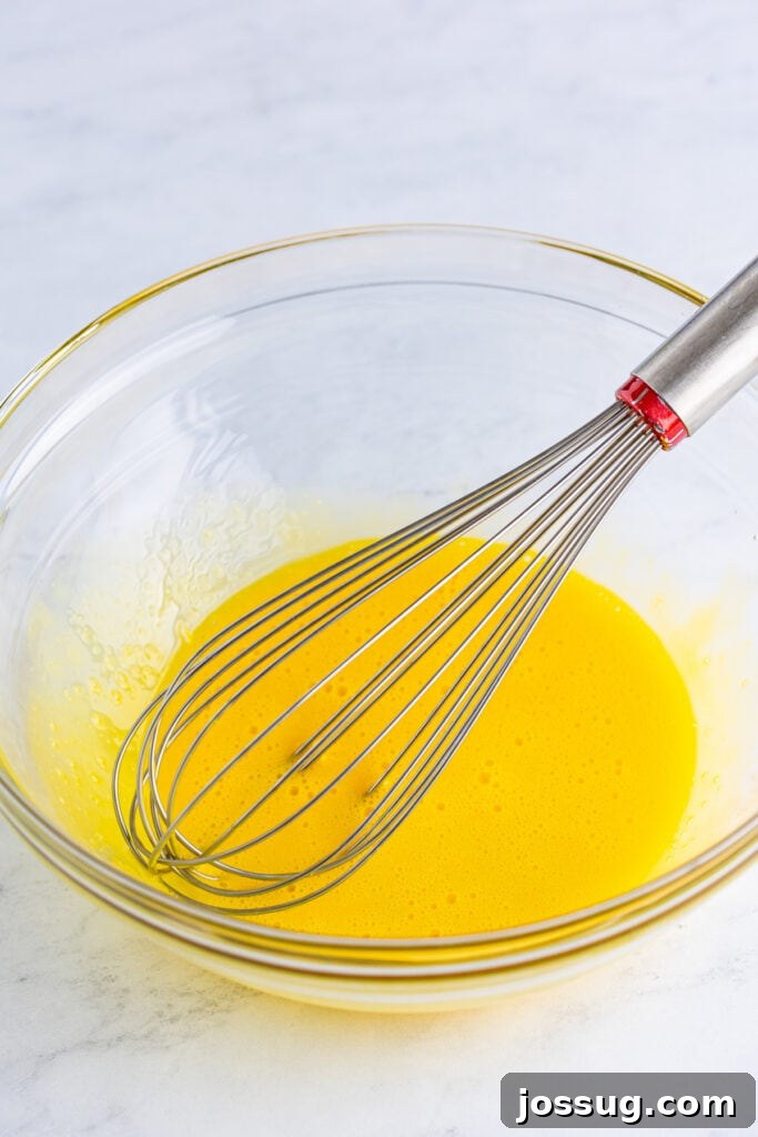 Creme Brulee Dream Trifle 4 Egg yolks being whisked in a glass bowl, preparing for the creamy creme brulee custard.