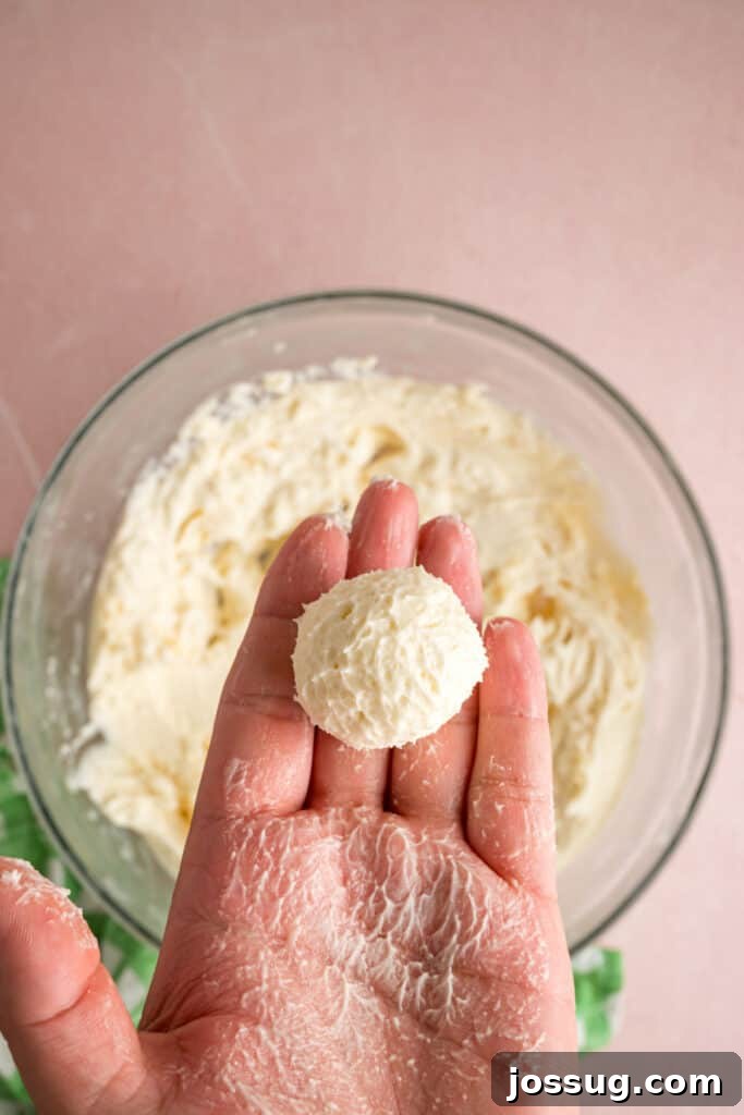 Buttercream Bliss Bites 11 Hand holding a rolled ball of buttercream filling above a glass mixing bowl