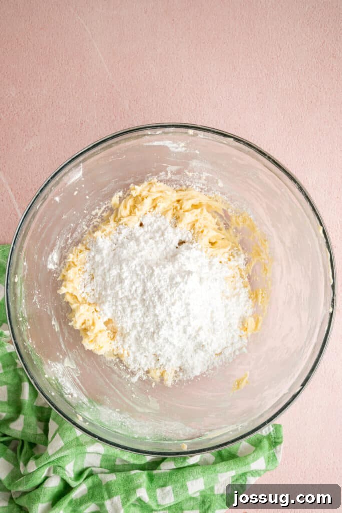 Buttercream Bliss Bites 7 Additional powdered sugar added to the butter mixture in a glass mixing bowl