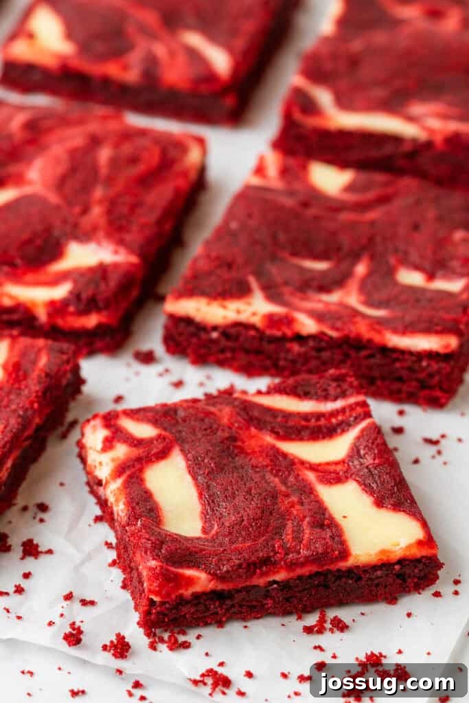 Delicious Red Velvet Cheesecake Brownies cut into squares with a cream cheese swirl