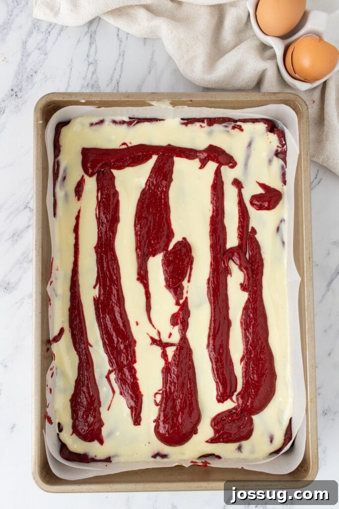 Red velvet batter dolloped over cream cheese layer