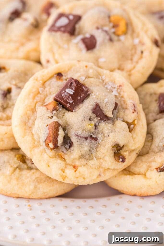 Pistachio Dream Cookies 2 Close-up of a pistachio chocolate chunk cookie with chocolate pieces and chopped pistachios, sprinkled with coarse salt.