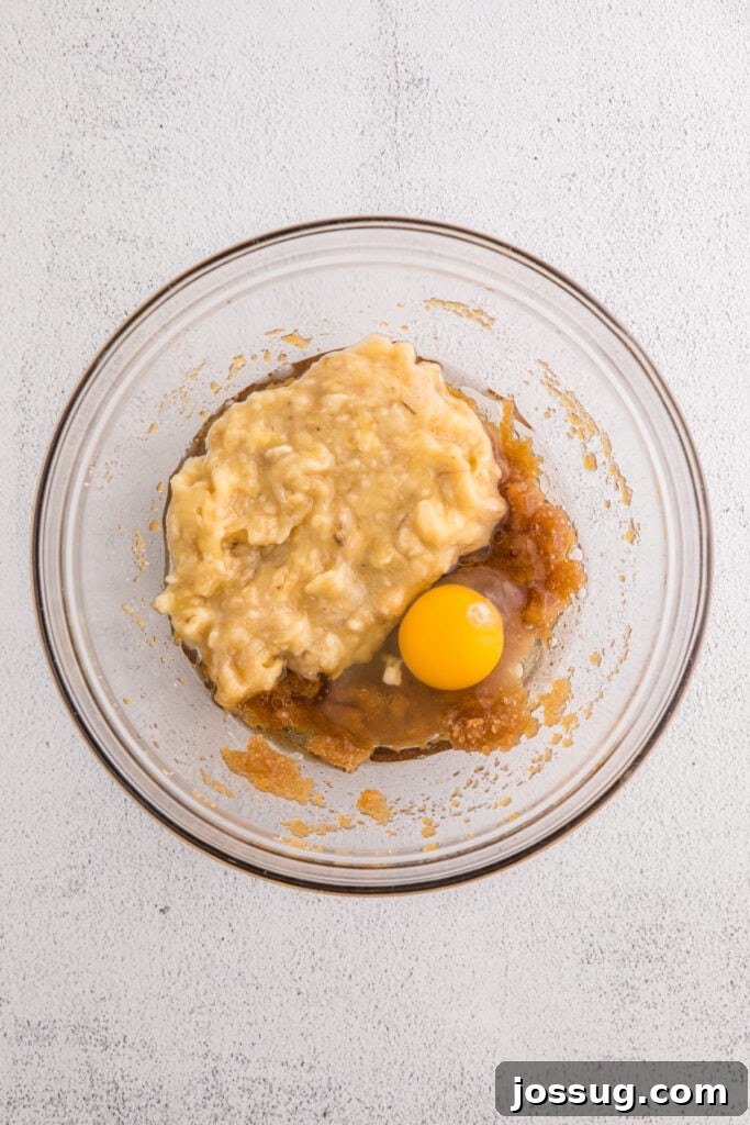 Banana Bread Brownies 6 Glass bowl with mashed bananas, egg, brown sugar mixture, and oil before mixing