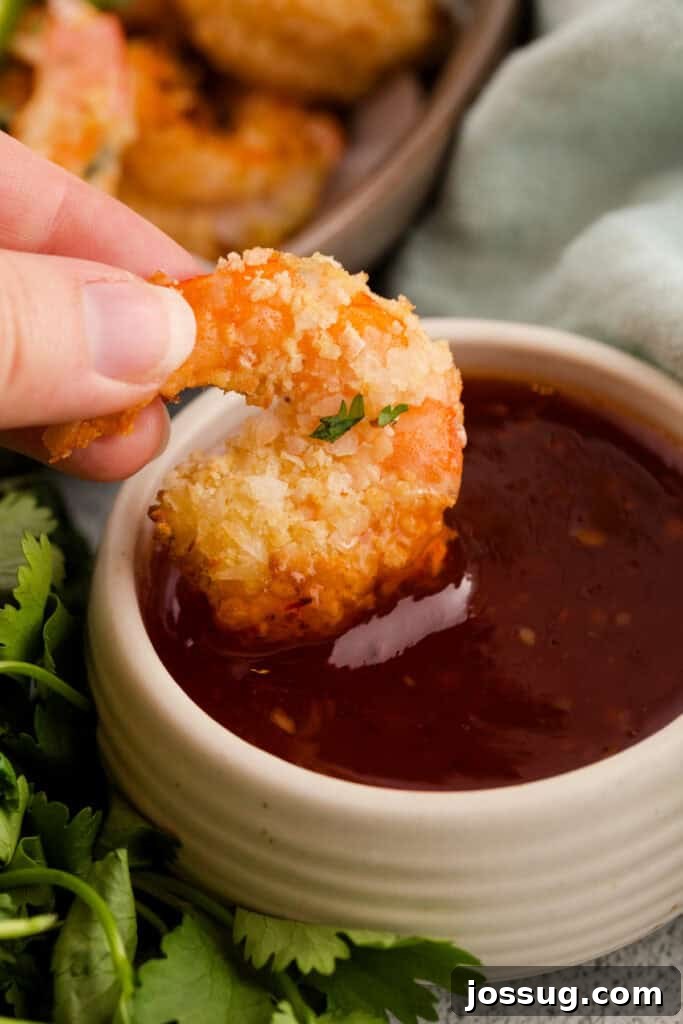 Air Fryer Coconut Shrimp Delight 9 Dipping coconut shrimp in sauce