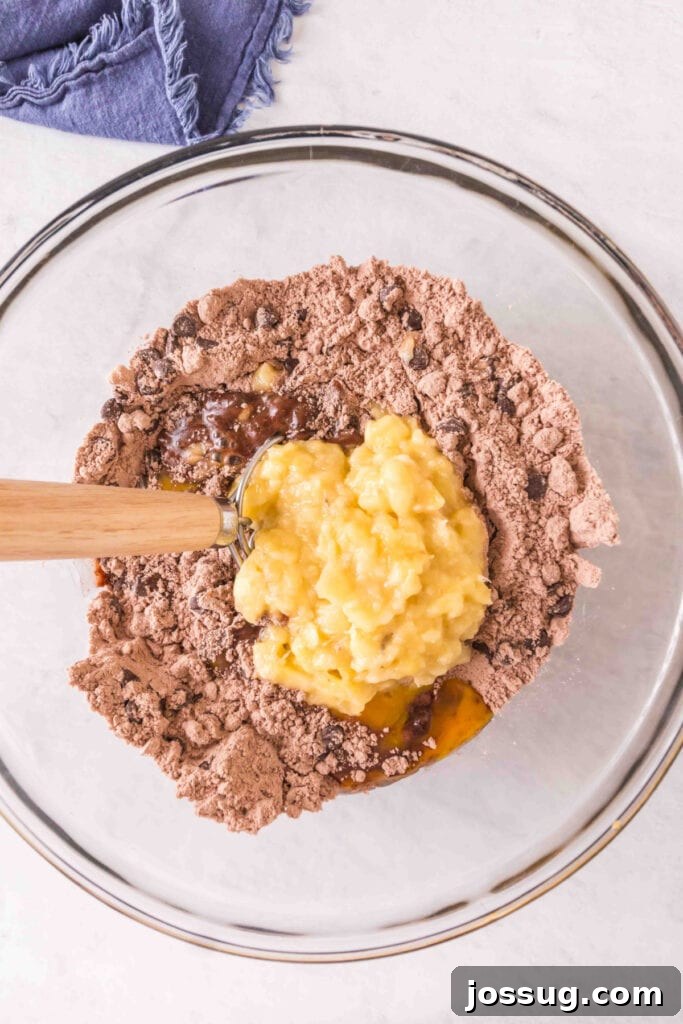 Brownie-Swirled Banana Bread 5 Mixing bowl with brownie mix, chocolate chips, walnuts, eggs, oil, and mashed bananas being added.
