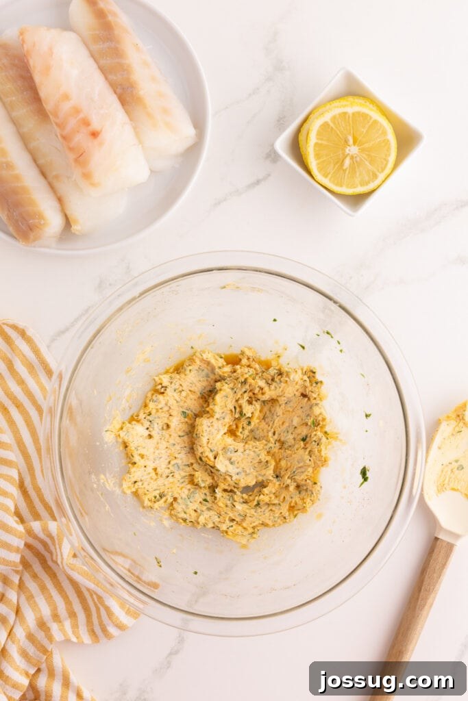 Glass bowl with garlic herb butter mixture fully combined, showing flecks of parsley and paprika throughout.