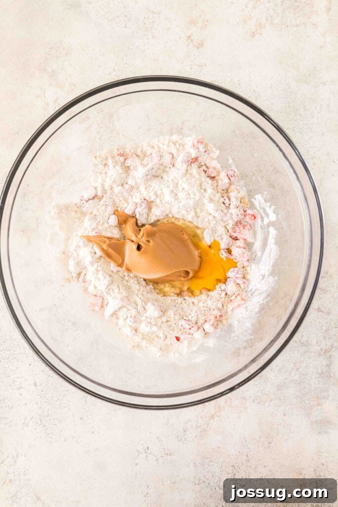 flour mixture with chopped strawberries, egg, and peanut butter in a glass mixing bowl