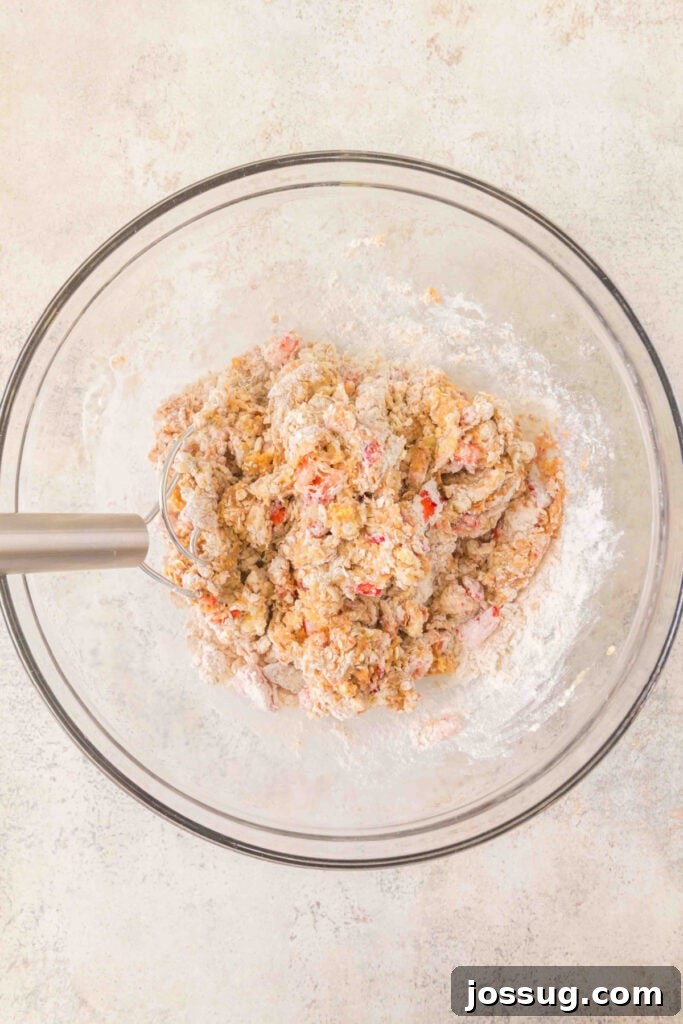 thick dog treat dough with strawberries and oats being mixed in a glass bowl