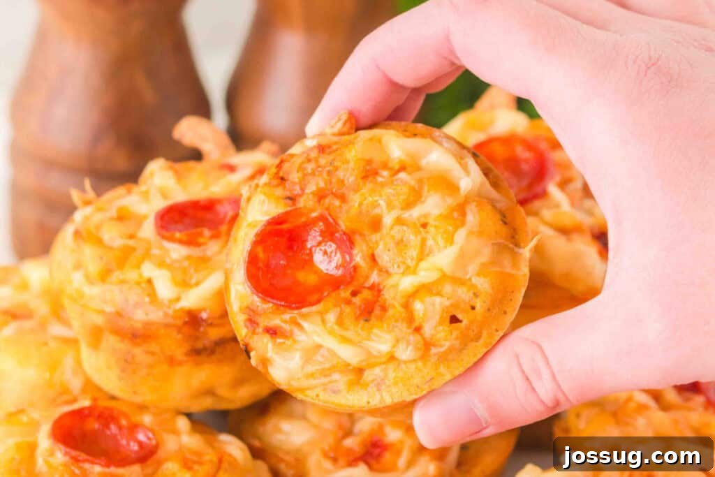 Pizza Muffin Magic: Bite-Sized Delights 4 Hand holding a delicious Pizza Muffin over a tray of muffins