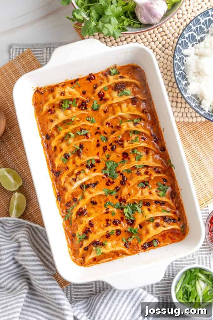 baked dumplings in coconut curry sauce in a white baking dish topped with cilantro and chili crunch