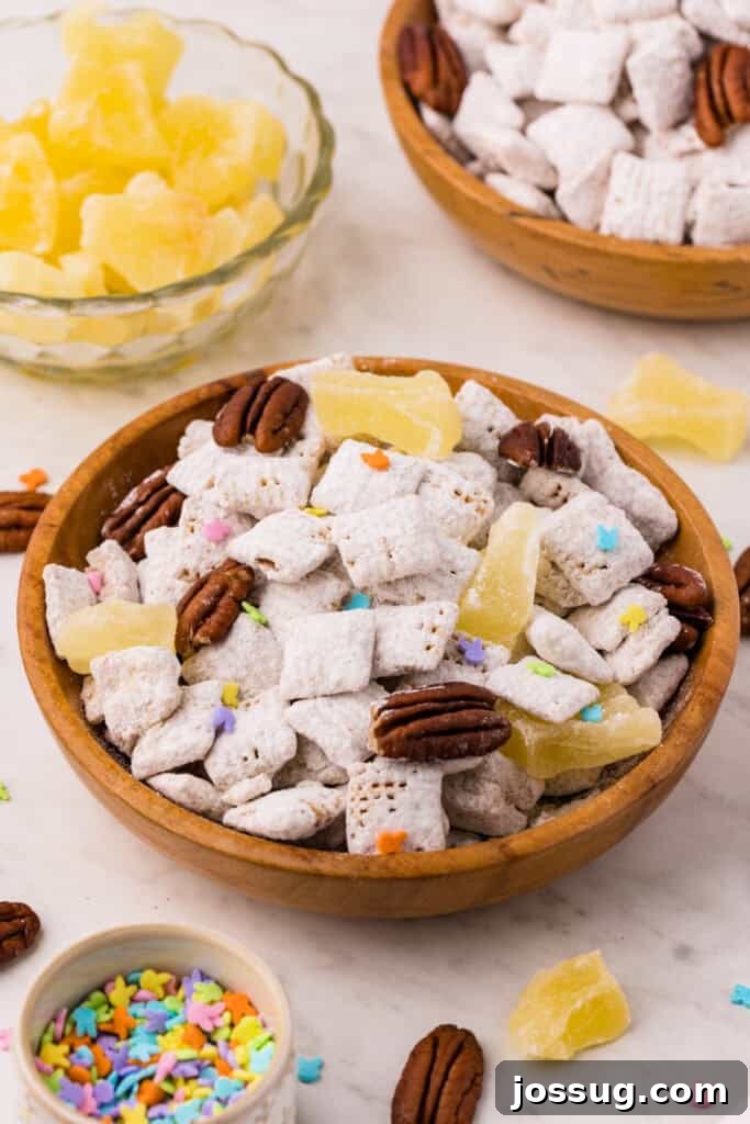 Carrot Cake Muddy Buddies: A Festive Spring Treat 2 Carrot cake muddy buddies in a wooden bowl with pecans, pineapple chunks, and pastel sprinkles