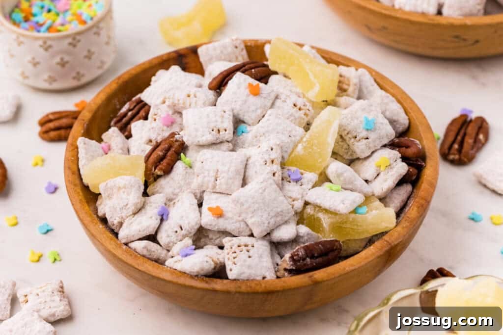 Carrot Cake Muddy Buddies: A Festive Spring Treat 4 Carrot cake muddy buddies in a wooden bowl with pecans, pineapple pieces, and colorful sprinkles on a countertop