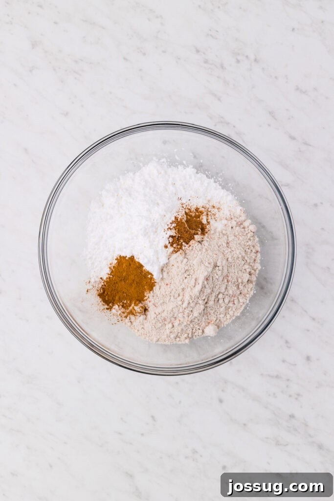 Carrot Cake Muddy Buddies: A Festive Spring Treat 5 Powdered sugar, carrot cake mix, cinnamon, and nutmeg in a glass mixing bowl before mixing