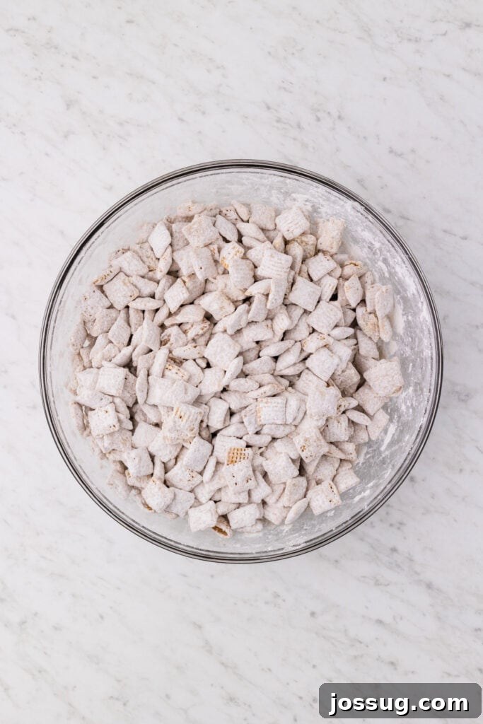 Carrot Cake Muddy Buddies: A Festive Spring Treat 10 Cereal coated in powdered sugar mixture in a large bowl
