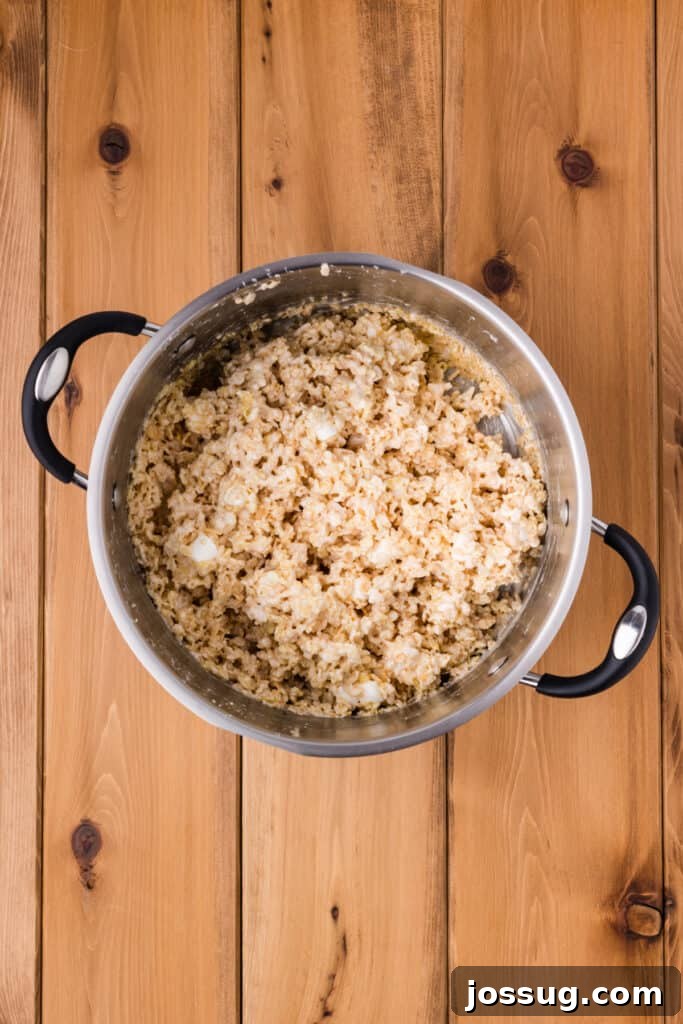 Crispy Rice Cereal Mixed with Melted Marshmallow Mixture in a Saucepan