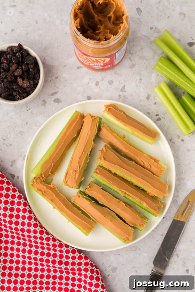 Ants on a Log: A Fun & Healthy Snack for Kids 6 Celery sticks filled with peanut butter on a plate with a butter knife and raisins nearby