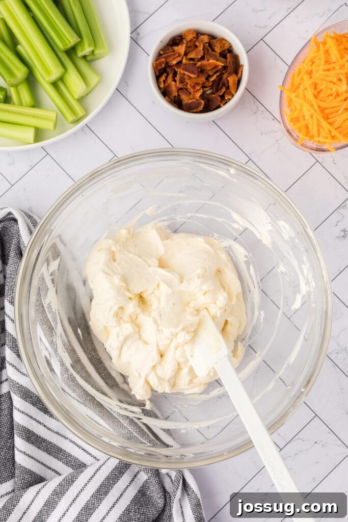 Smooth cream cheese mixture in a glass bowl with spatula after mixing
