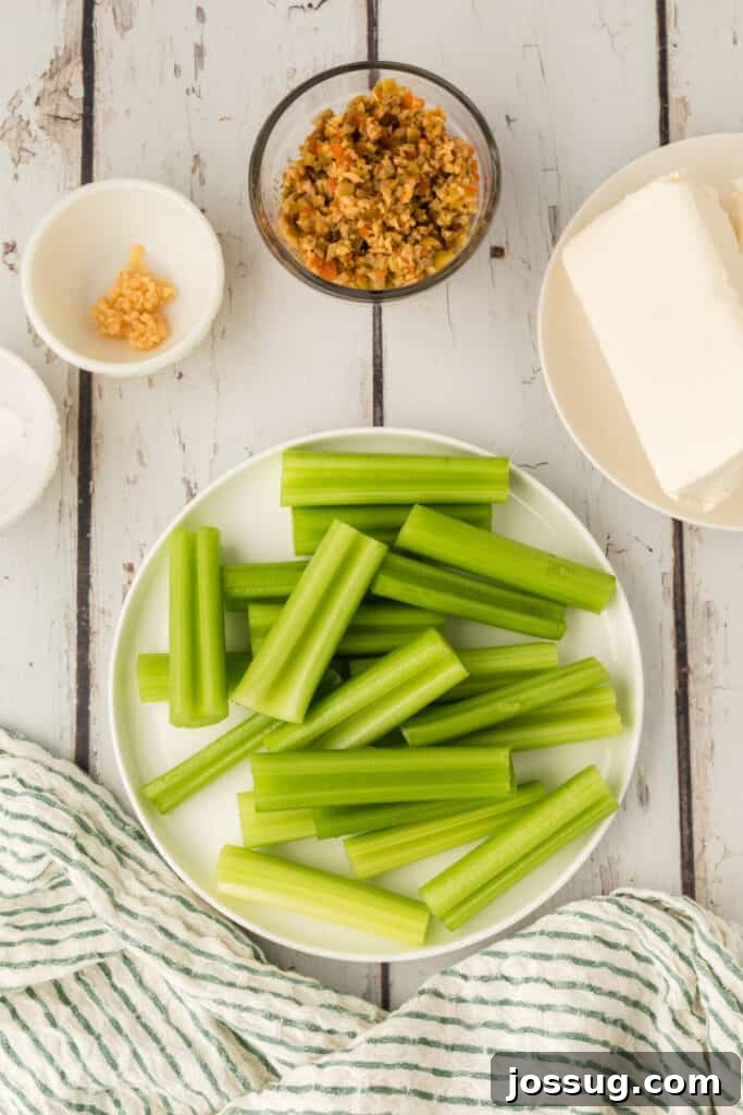 Cut celery pieces arranged on a plate with cream cheese, chopped olives, and garlic nearby