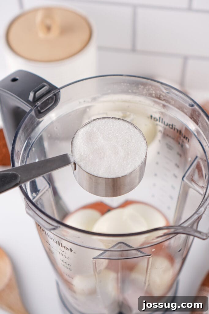 Chocolate Infused Custard Eggs 7 Measuring cup of granulated sugar held over blender with hard boiled eggs inside