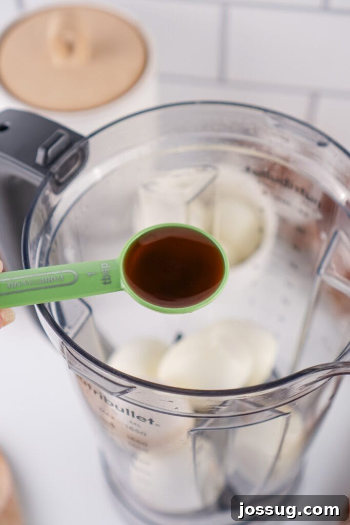 Chocolate Infused Custard Eggs 8 Tablespoon of vanilla extract held over blender with hard boiled eggs inside