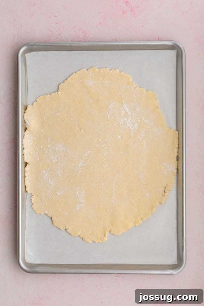 Simply Irresistible Strawberry Rhubarb Galette 13 The perfectly rolled-out galette dough is carefully placed onto a parchment-lined baking sheet, providing a non-stick surface for baking.