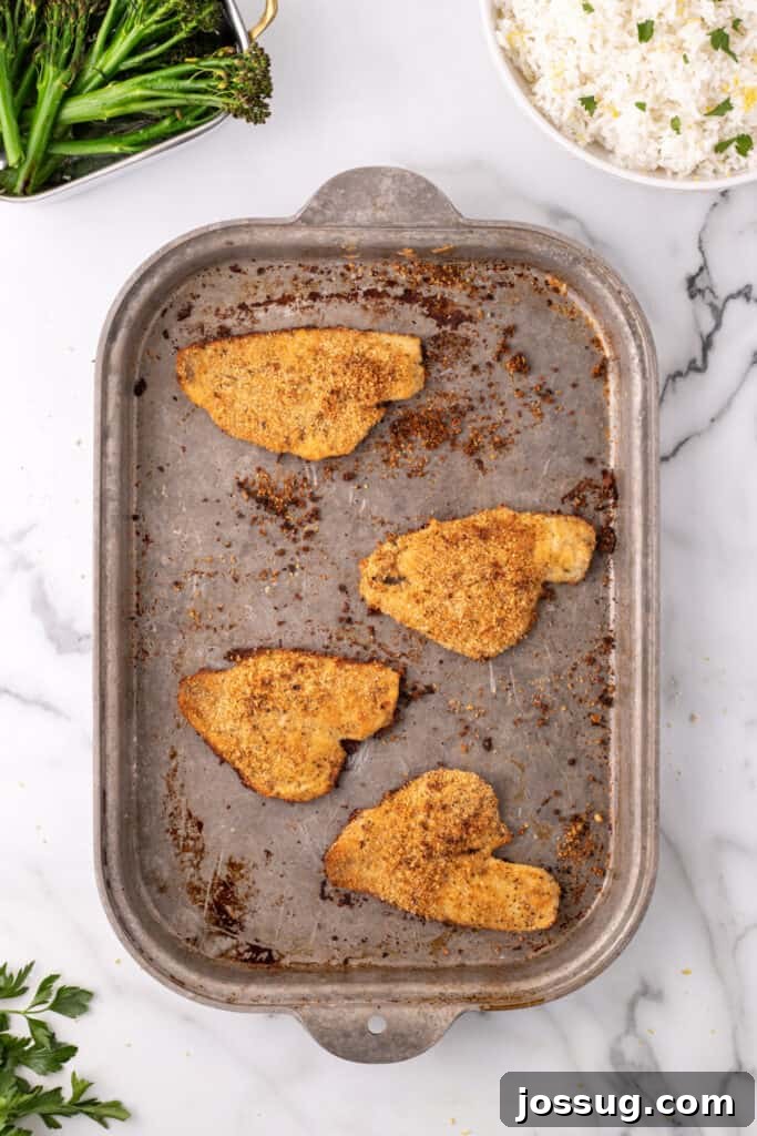 Baked flounder fillets on a baking sheet with browned breadcrumb coating, just out of the oven.