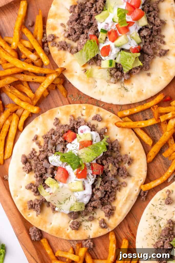 Hafta İçi Akşamlarına Özel Kolay Yunan Kıymalı Pide 16 A complete serving of Greek Ground Beef Pitas, topped with fresh vegetables and yogurt sauce, accompanied by crispy fries for a full meal.