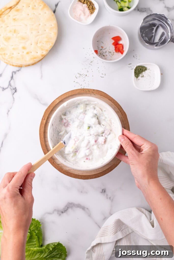 Hafta İçi Akşamlarına Özel Kolay Yunan Kıymalı Pide 8 A bowl of Greek yogurt perfectly mixed with chopped cucumber, tomato, and fresh herbs, showcasing the finished creamy sauce.