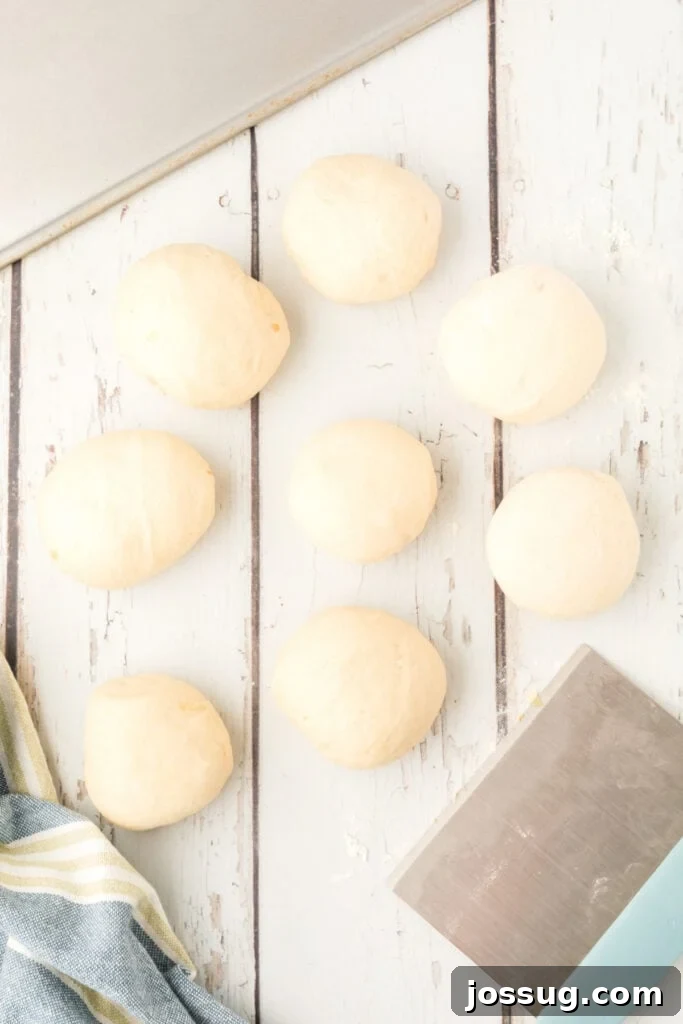8 dough balls shaped for homemade onion rolls on a floured surface