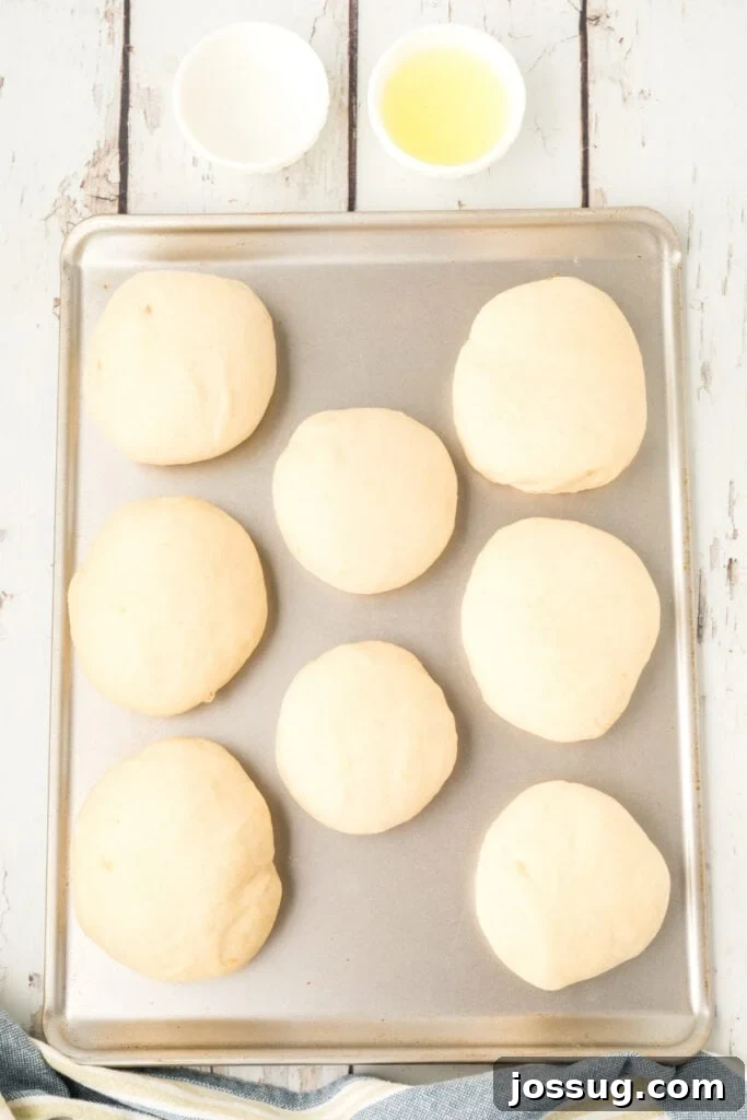 risen homemade onion rolls dough on a baking sheet with egg wash and a small bowl of egg mixture