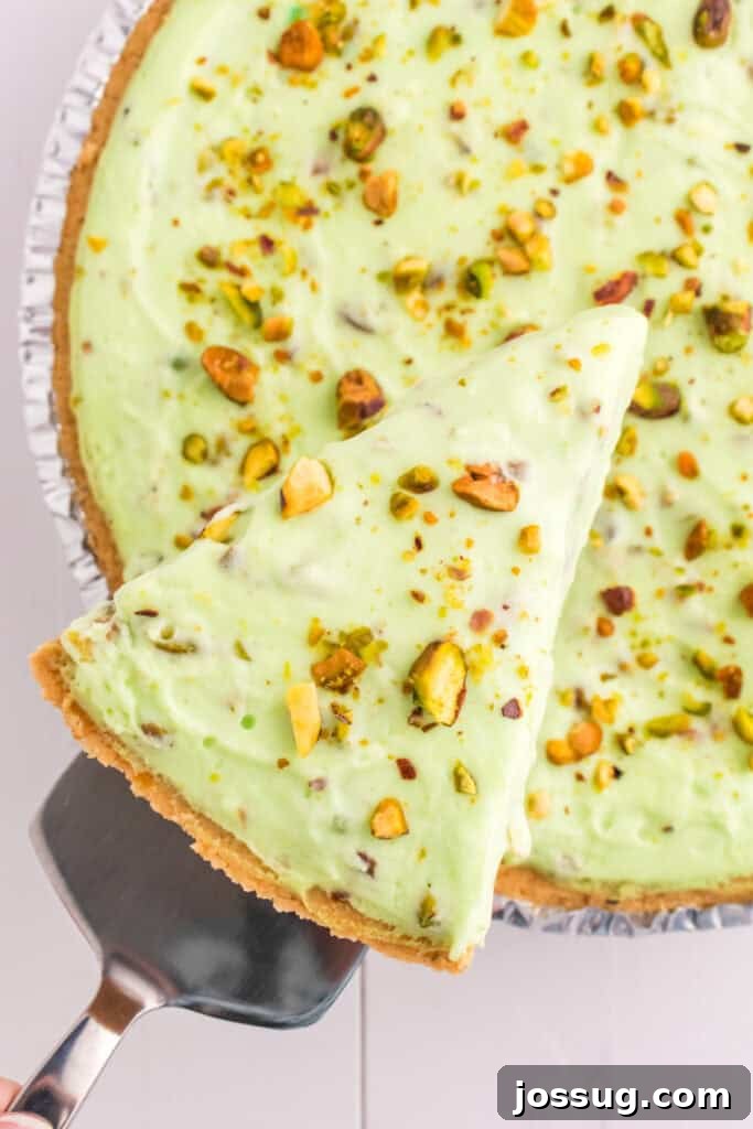Quick No Bake Pistachio Delight 17 A delectable slice of No Bake Pistachio Cream Pie being gently lifted from the full pie with a spatula, showcasing its perfect set and creamy texture.
