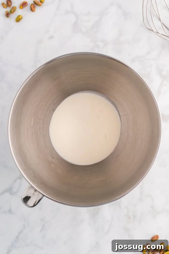 Quick No Bake Pistachio Delight 6 A mixing bowl filled with cold heavy cream, perfectly prepared and ready to be whipped into fluffy peaks.
