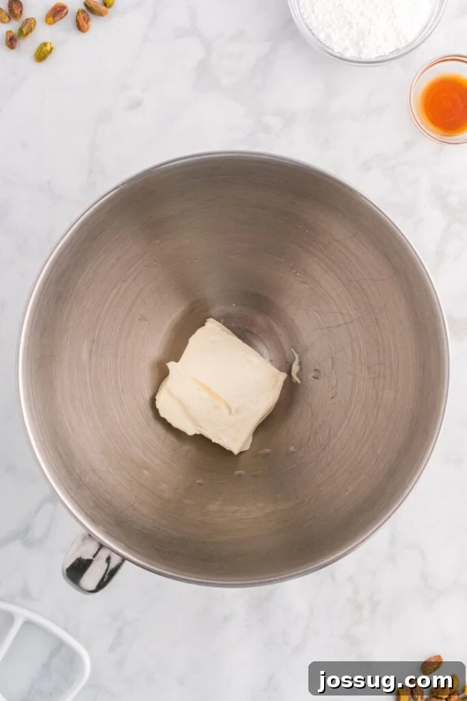 Quick No Bake Pistachio Delight 8 A block of softened cream cheese resting in a mixing bowl, perfectly prepped for beating to achieve a smooth and creamy texture.
