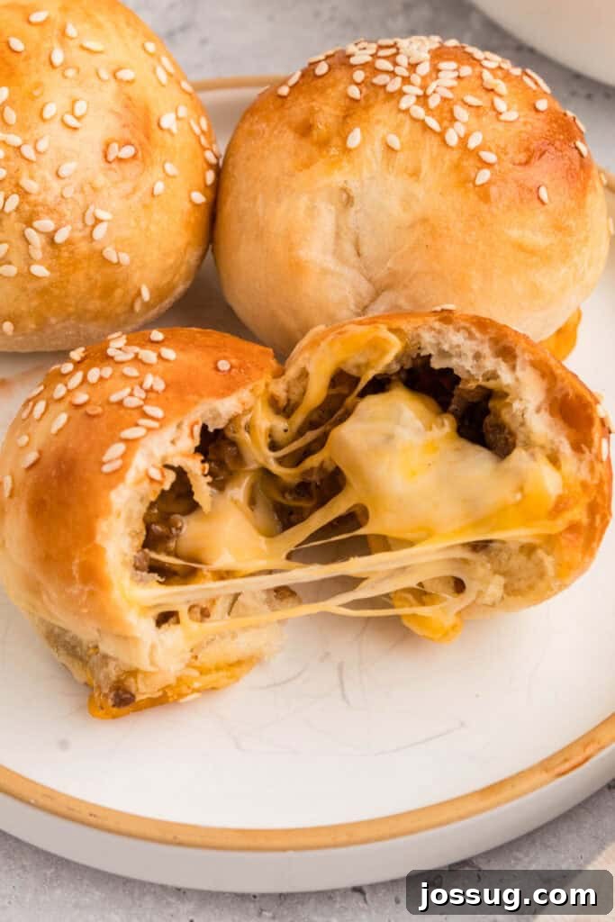 burger bombs on a plate with one cut open showing melted cheese and ground beef filling