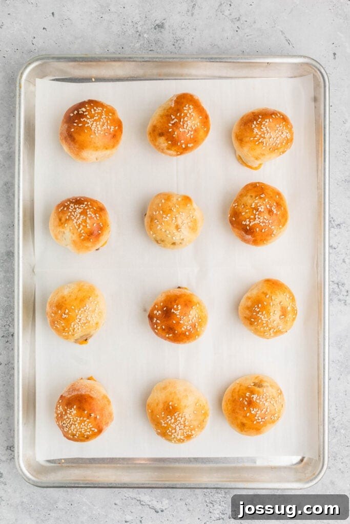 baked burger bombs with sesame seeds on a baking sheet