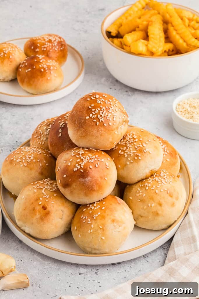 plate of baked burger bombs with sesame seeds and a bowl of fries in the background