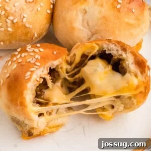 close-up of a burger bomb split open with melted cheese stretching and sesame seeds on top