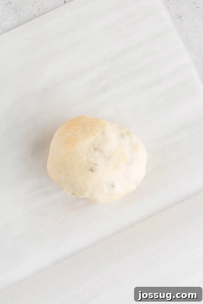 dough wrapped around filling forming a sealed ball on parchment paper