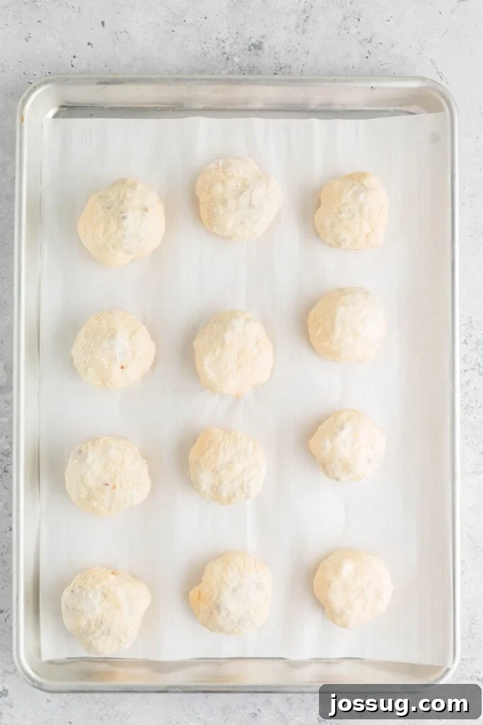 unbaked burger bombs arranged on a parchment-lined baking sheet