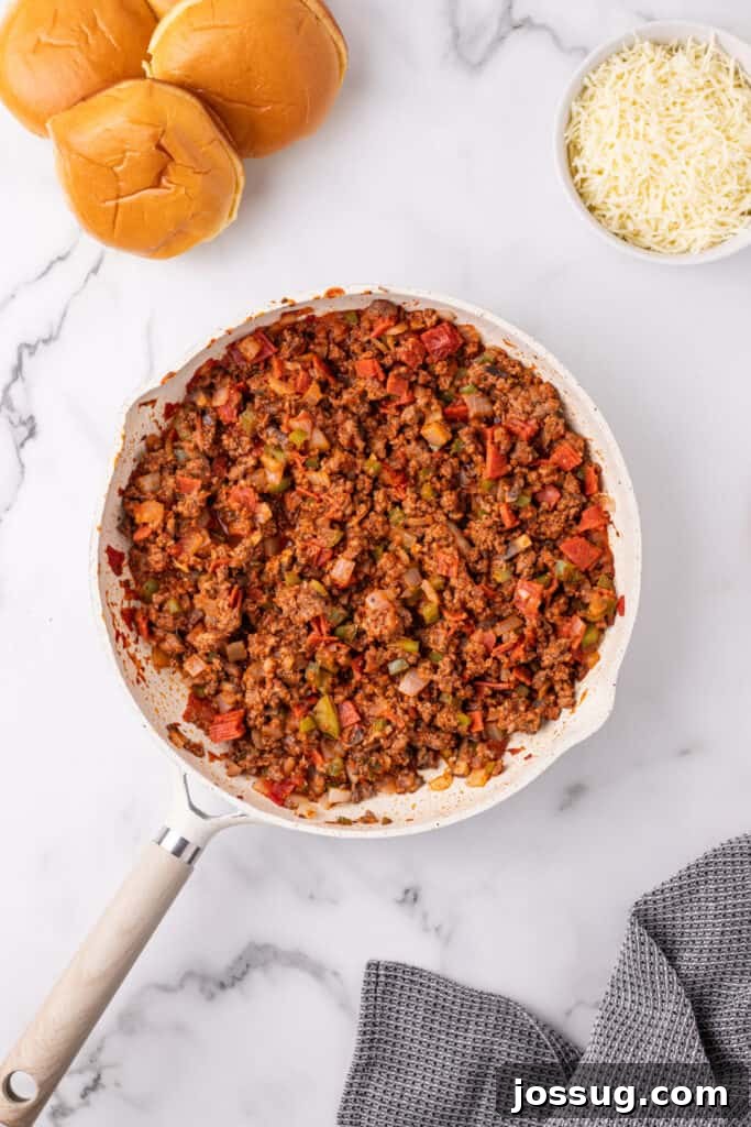 Easy Ground Beef Pizza Sloppy Joes 8 fully cooked Pizza Sloppy Joes meat mixture in a skillet with hamburger buns and shredded cheese nearby