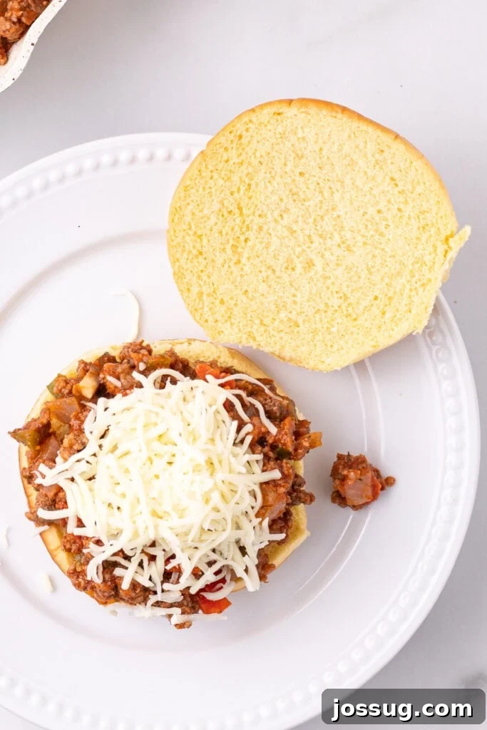 Easy Ground Beef Pizza Sloppy Joes 10 shredded mozzarella cheese added on top of Pizza Sloppy Joes filling on a hamburger bun