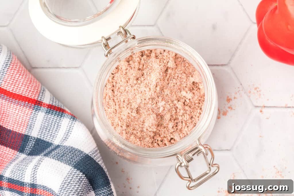 An overhead shot of the finished homemade fajita seasoning stored in a clear glass jar with a cork lid.