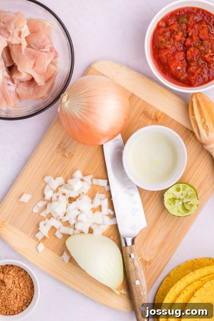 Crockpot Shredded Chicken Tacos Recipe for Busy Weeknights 5 Chopped onion, lime juice, salsa, and raw chicken prepared for Crockpot Shredded Chicken Tacos on a cutting board
