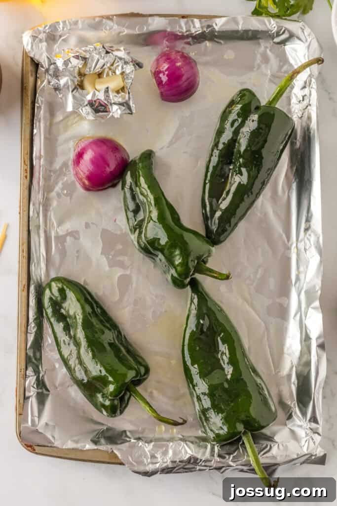Creamy Mexican Verde Spaghetti (Espagueti Verde) 5 Poblano peppers, garlic, and red onion on baking sheet for Mexican Green Spaghetti recipe