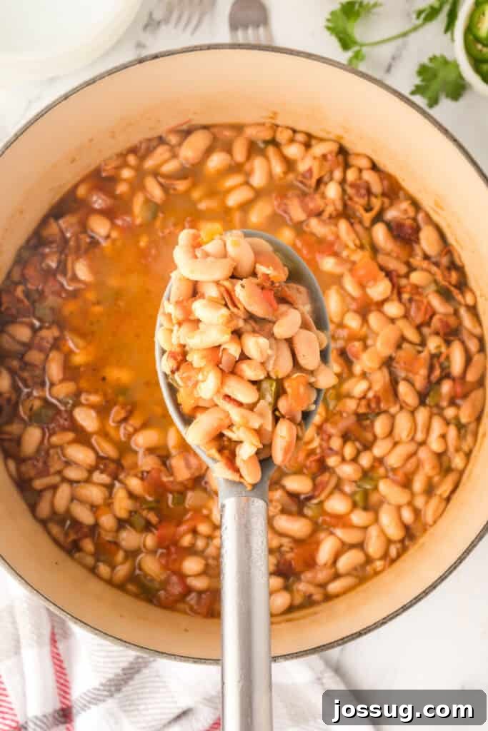 Ranchero Pinto Beans with Bacon — Flavorful Skillet Recipe 13 Spoonful of Ranchero Beans with bacon, tomatoes, and jalapeño over a Dutch oven