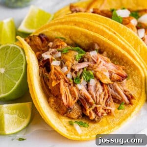 Square image of Slow Cooker Carnitas taco with lime wedges and cilantro