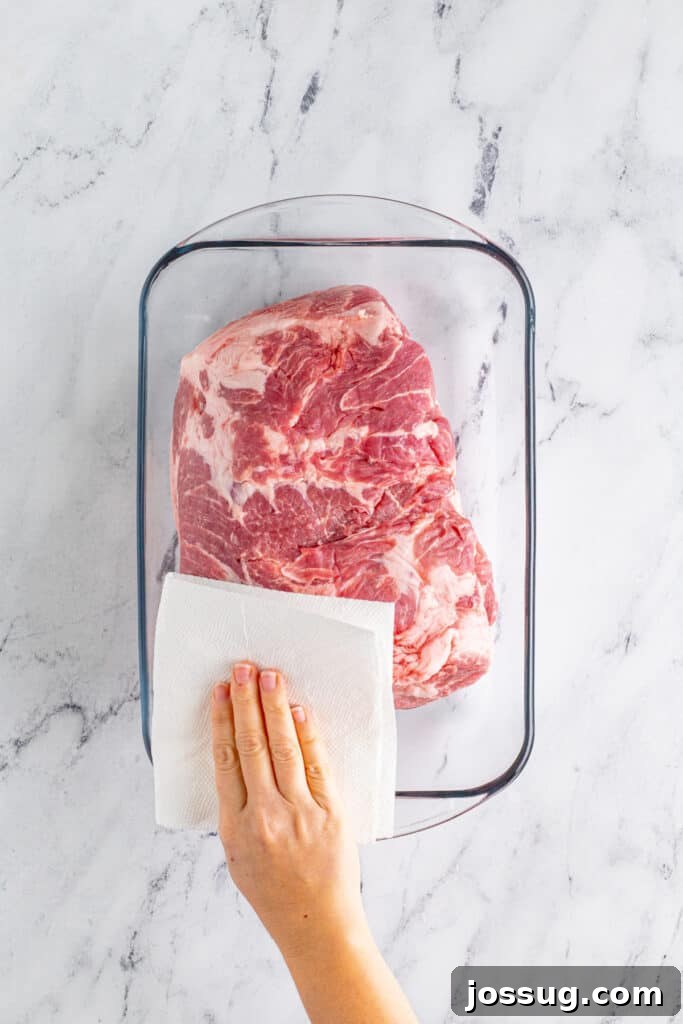 Patting dry pork shoulder for Slow Cooker Carnitas recipe