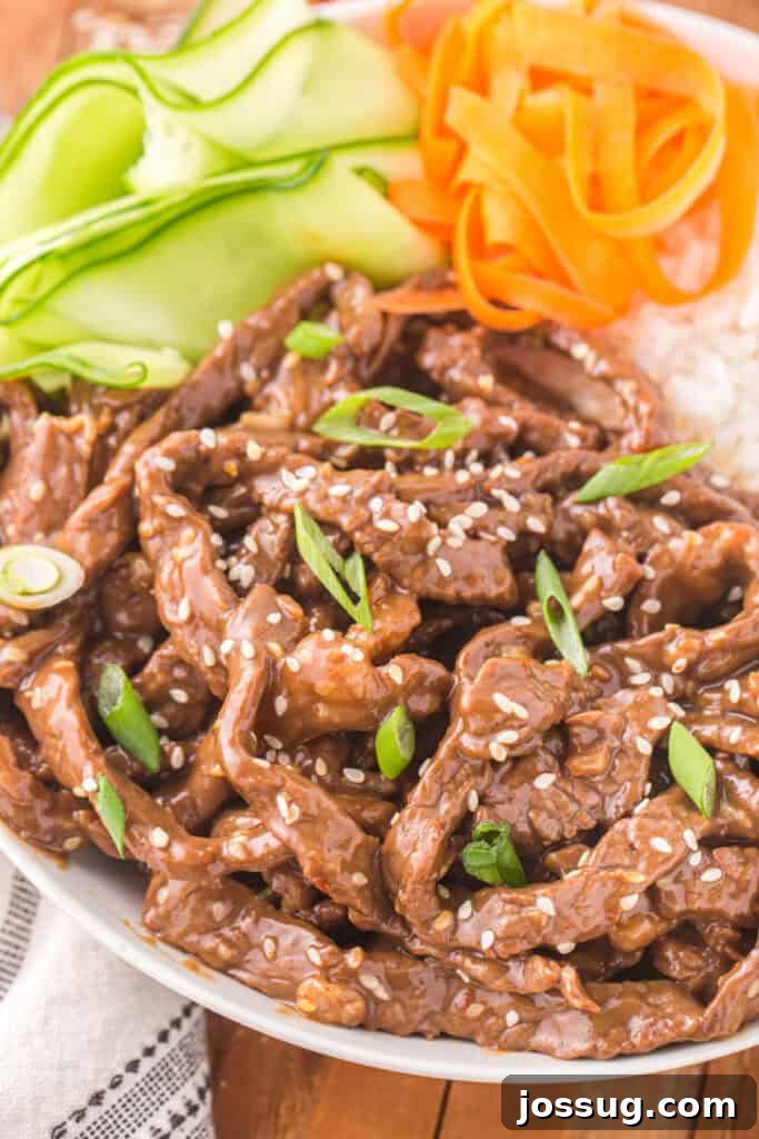 Close-up of Korean Beef Bulgogi with sesame seeds and green onions served with rice and vegetables