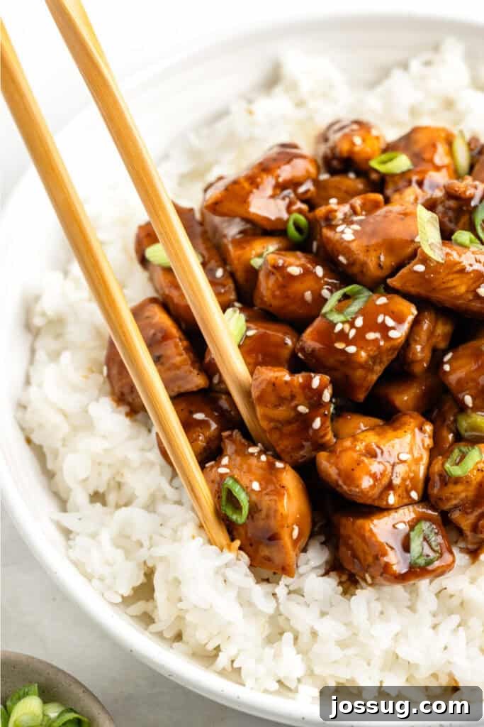Chicken Teriyaki rice bowl with chopsticks, sesame seeds, and sliced green onions